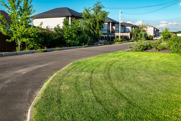 Perfectly mowed lawn and asphalt road in the village