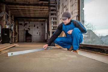 Worker with level tool measures concrete floor