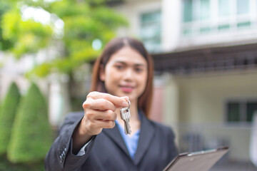 Young asian woman holding the key with new house. Real Estate Agent giving house keys.