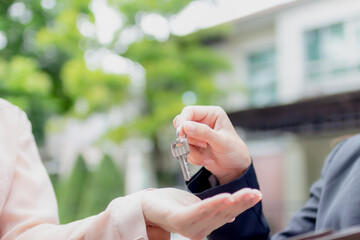 Young asian woman holding the key with new house. Real Estate Agent giving house keys.