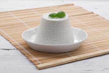 cottage cheese on white plate resting on wooden placemat with white wood background