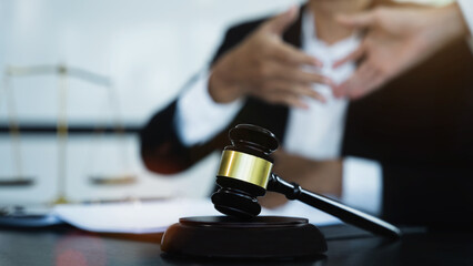 Close up view of auction hammer on the desk in lawyer office and lawyer writing document as courtroom.