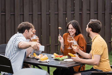 cheerful multiethnic friends taking selfie while laughing during bbq party in backyard