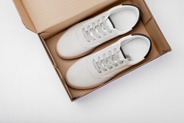 One white casual sneakers in a brown cardboard box