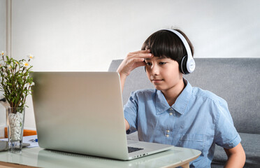 Confusing student boy focused on online exams or tests by using laptop sitting desk at home. Preteen child struck on the lesson in online class. Tenn Education Technology Self Improvement Concept