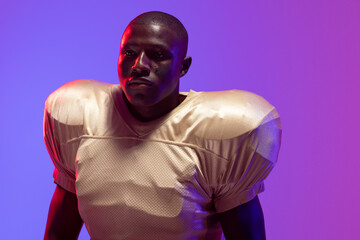 Fototapeta na wymiar African american male american football player with neon blue and purple lighting