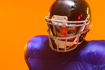 Caucasian male american football player wearing helmet with neon orange lighting © wavebreak3