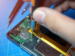 Smartphone technician repairing the motherboard of a smartphone on service lab desk. Electronic...