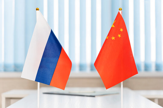 Political flags of russia and chinese on table in international negotiation room. concept of negotiations, collaboration and cooperation of countries. agreement between governments.