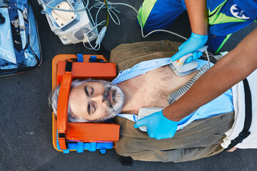 Ambulance paramedic using defibrillator performing cardiopulmonary resuscitation on casualty. First...