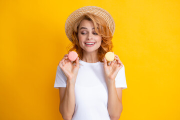 Woman eating a macaroon. Beautiful redhead woman in summer straw hat eating sweet macaroons. French dessert, sweets.