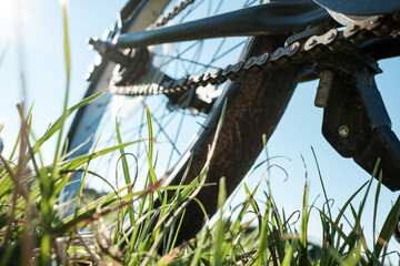 Close-up detail of a bicycle parked in a meadow, against the backdrop of the sun and blue sky. Active lifestyle concept. Bottom view.