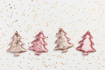 Christmas holiday pink beige decorations trend sparkling xmas toys from metallic sequins, shining Christmas trees and golden stars around. New Year background, Happy holidays concept, top view