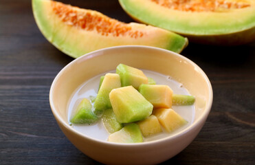 Delectable Thai Melon in Chilled Sweet Coconut Milk with Blurry Fresh Fruit in the Backdrop