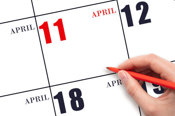 A hand holding a red pen and pointing on the calendar date April 11. Red calendar date, copy space,...