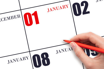 A hand holding a red pen and pointing on the calendar date January 1. Red calendar date, copy...