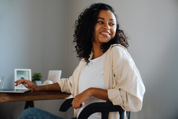 African american young woman sitting at desk and using laptop at home