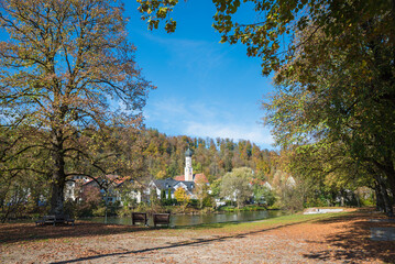 Isar riverside with autumnal trees and benches, spa town Wolfratshausen, beautiful destination...