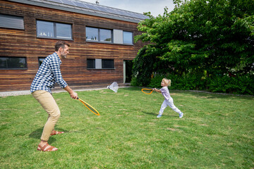 Family happy moments in backyard father and daughter play badminton
