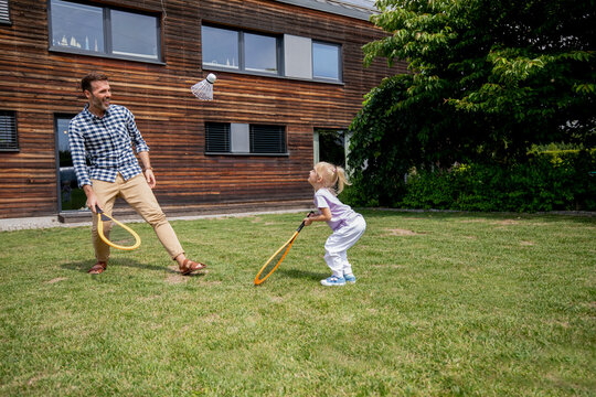 Father and his daughter playing badminton together in their backyard