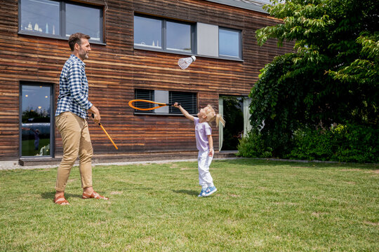 Father and his daughter playing badminton together in their backyard