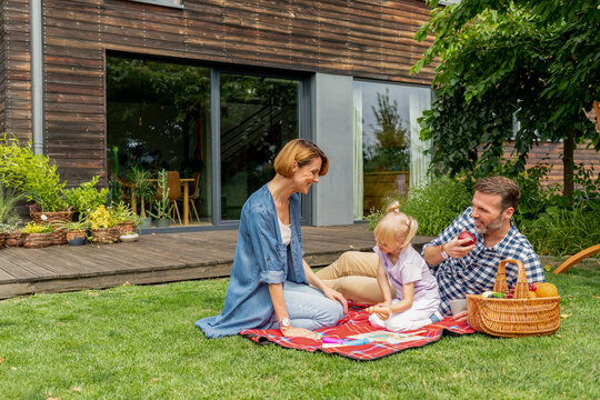 Happy family picnic in backyard in front of their house