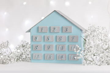 Blue and silver advent calendar for two weeks in the shape of a house. Preparing for Merry...