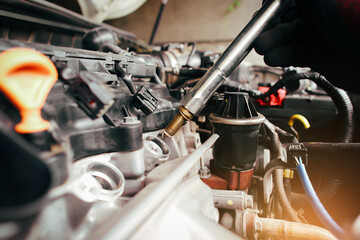 A auto mechanic is installing automobile iridium spark plugs into the ignition spark socket of the...