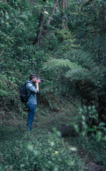 Obraz premium Caucasian photographer taking photos in the middle of the forest