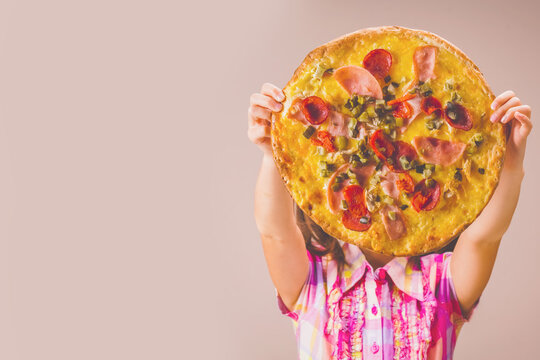 Pretty young girl holding pizza in front of their faces. She having fun eating dinner. Copy spaace.