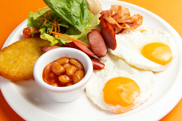 Traditional breakfast. Fried sausage eggs and hash brown in a plate.