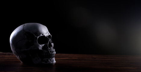 Halloween human skull on an old wooden table over black background. Shape of skull bone for Death...