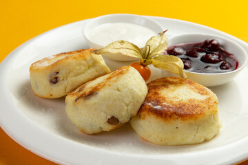 Traditional breakfast syrniki in a plate on a yellow background.