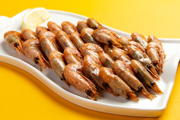 Fried shrimp in a plate on a yellow background.