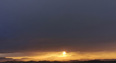 hdr Il sole al tramonto illumina le montagne in un cielo di nuvole nere