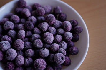 Close up of frozen blueberries in a white bowl.
