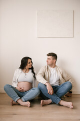 Young pregnant woman with husband at home, happy family and pregnancy concept