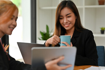 Two businesswomen considering project, concentrated young women workers discuss business startup, cooperation concept.