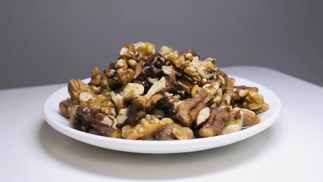 Peeled walnut kernels rotating on plate, healthy vegetarian protein diet food