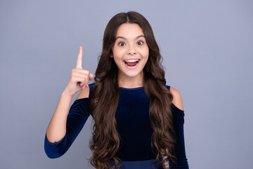 Excited teenager girl. Portrait of cute teenager pointing up with finger. Girl has great new idea. Successful child.