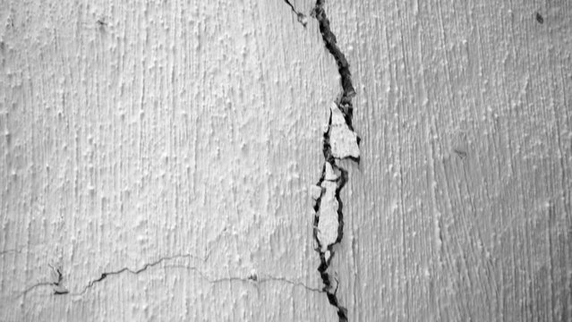 Long crack in the white ceiling of an old rural house close-up. The camera moves along a crack in the clay wall. The rapid destruction of the dwelling and the loss of integrity. after the earthquake
