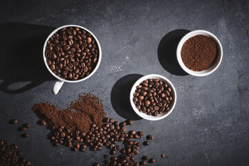 White cup of freshly brewed roasted coffee beans on gray background