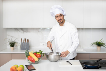 Young handsome male chef is cooking in the kitchen