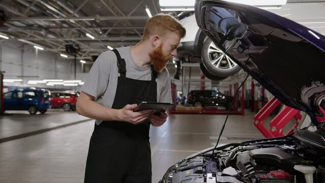 Troubleshooting in the car using a tablet and a master mechanic. Car repair station