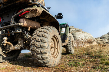 Close-up detail bottom POV view 4x4 awd ATV vehicle on dirt gravel unpaved road in autumn at misty...