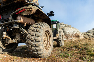 Close-up detail bottom POV view 4x4 awd ATV vehicle on dirt gravel unpaved road in autumn at misty mountain top. Offroad car mountain safari adventure nature trial journey concept. Quad bike rental © Kyryl Gorlov