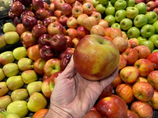 Retail grocery store hand holding a Fuji apple