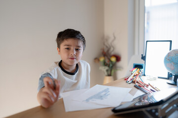 School kid using grey colour pen drawing or sketching on paper,Portrait  boy siting alone and looking out with thinking face, ,Child enjoy art and craft activity at home on weekend,Education concept