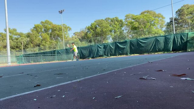 Man hitting yellow tennis ball with the racket. Male tennis player during outdoor training. High quality 4k footage. Monsanto courts in Portugal.