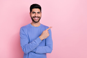 Photo of attractive cheerful arab guy dressed blue pullover pointing empty space isolated pink...